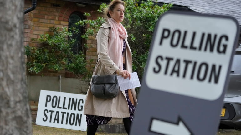 A woman holds her voting card as she arrives to...