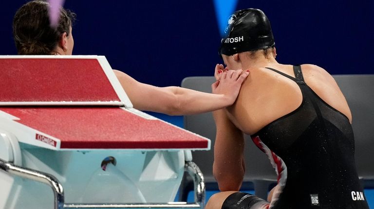 A teammate comforts Canada's Summer McIntosh at the end of...