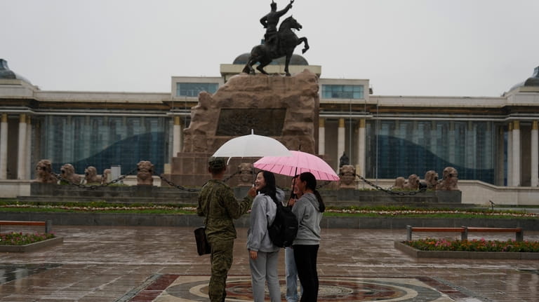 Young Mongolians chat under umbrellas as it rains on Sukhbaatar...