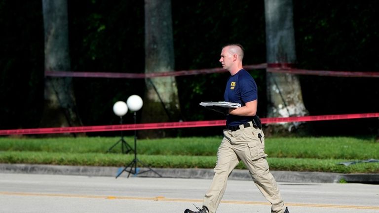 An FBI officer works outside of Trump International Golf Club...