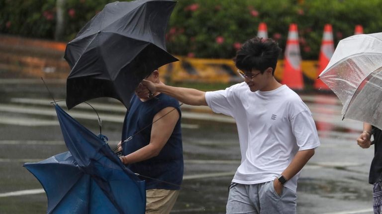 Two men struggle with their umbrellas against gusts of wind...