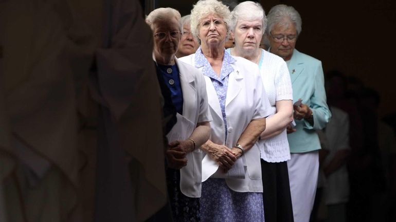 Mourners look on as Sister Jacqueline Walsh's casket is carried...