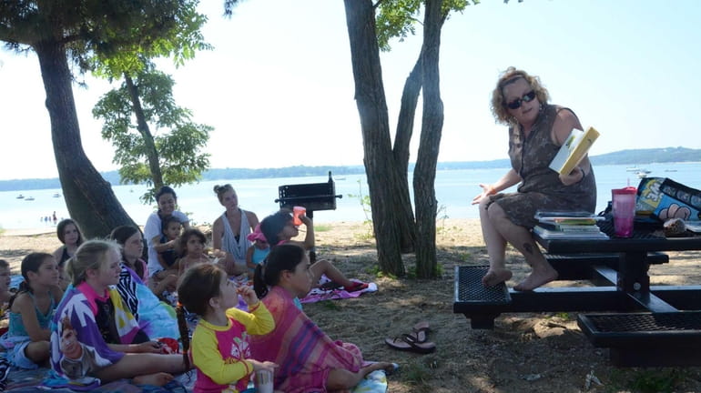 Librarian Jill Abbatangelo reads stories to kids gathered at West...