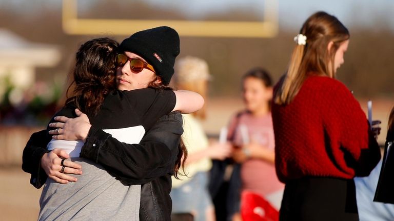 People embrace at a vigil in Tishomingo, Okla., March 25,...