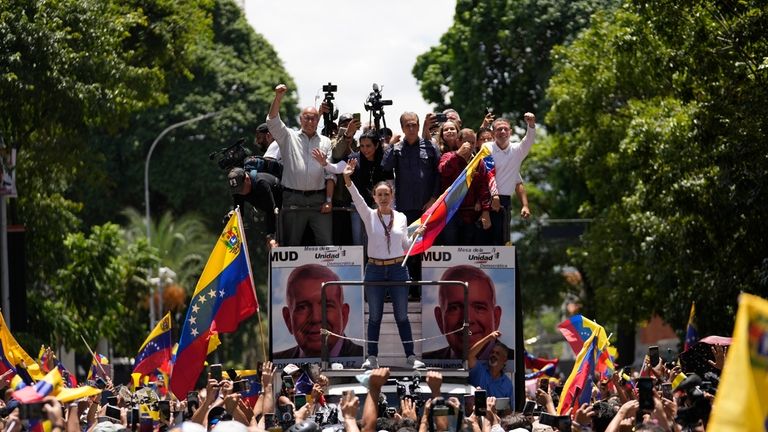 Opposition leader Maria Corina Machado holds a national flag while...