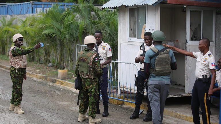 A Kenyan police officer takes candid photos as Haitian and...