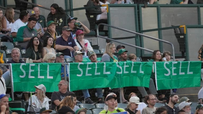 Signs calling for Oakland Athletics management to sell the team...