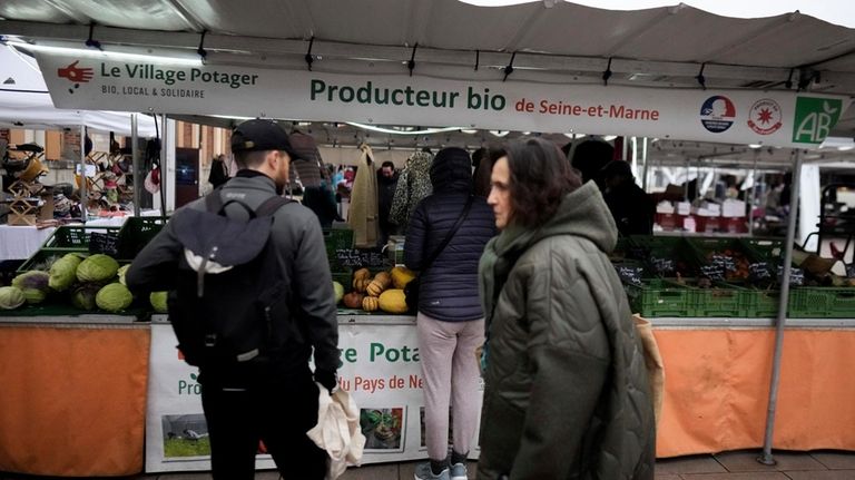 People shop at an organic food seller in an open...