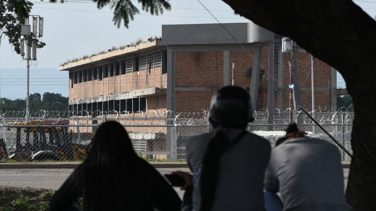 Relatives of detainees sit outside the Tocuyito jail as they...