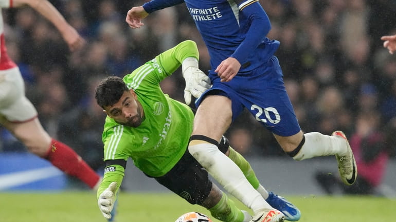 Chelsea's Cole Palmer goes with the ball past Arsenal's goalkeeper...