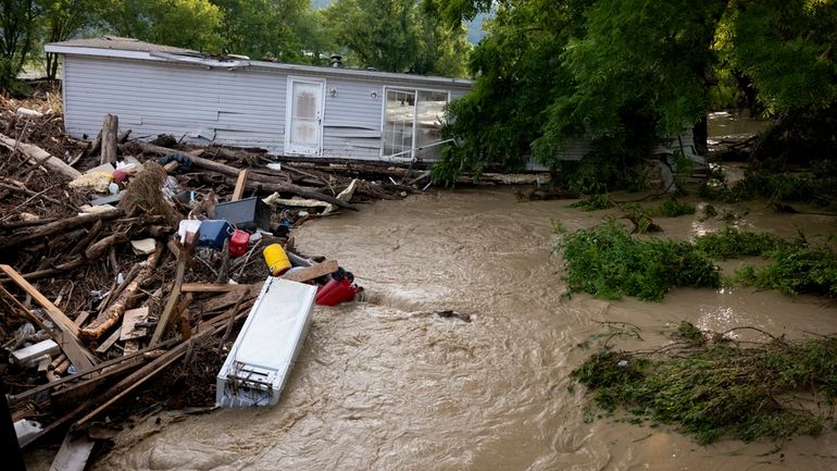 A mobile home swept from its foundation is seen lodged...