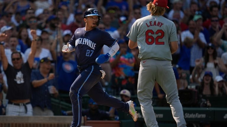 Chicago Cubs' Seiya Suzuki, left, runs by St. Louis Cardinals...