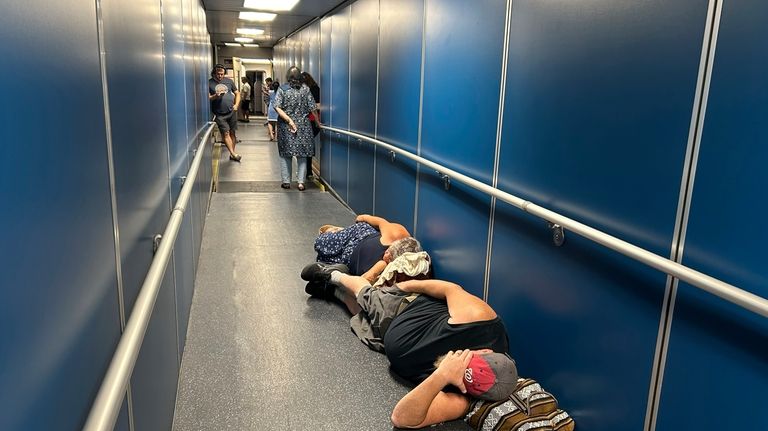 Travelers at Los Angeles International Airport sleep in a jetway...