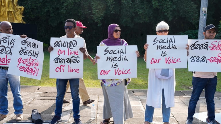Sri Lankan social media activists hold placards with slogans against...