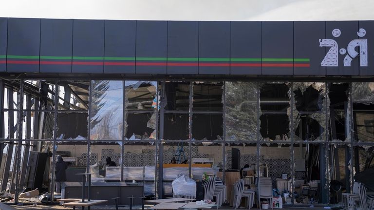 Local citizens clean a shop that was damaged after Russians...