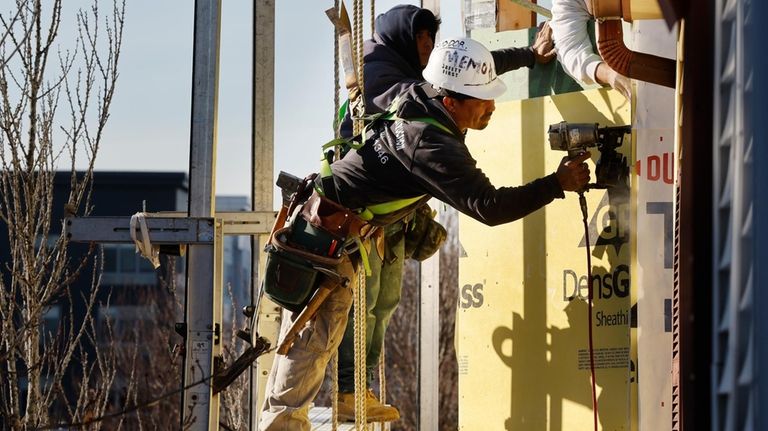 Workers apply sheathing to the exterior of a new multifamily...