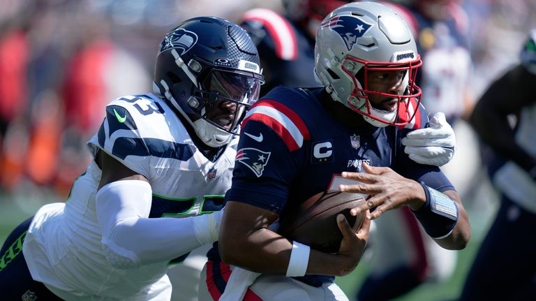 New England Patriots quarterback Jacoby Brissett, right, is brought down...