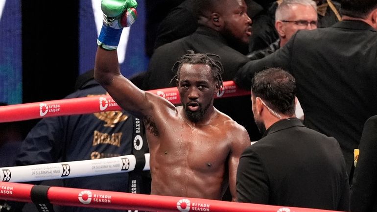 Terence Crawford, center, raises his fist as at the end...