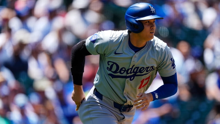 Los Angeles Dodgers' Shohei Ohtani heads up the first-base line...