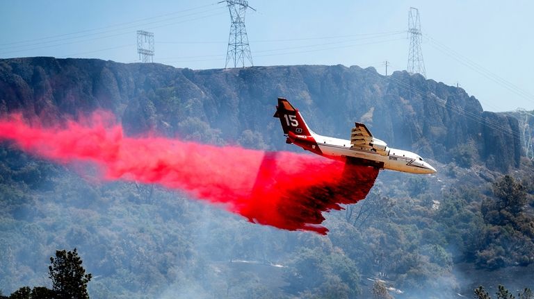 An air tanker drops retardant while trying to stop the...