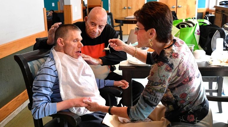 Vicki Laufer feeds lunch to her brother Ricky as Harvey Weisenberg...