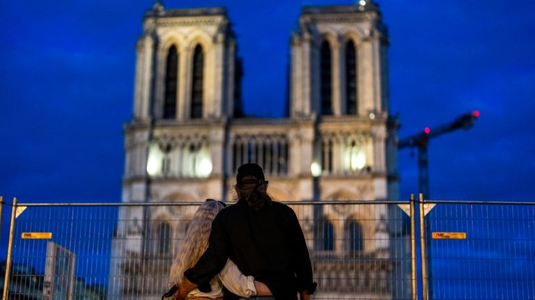 A couple stand next to a security fence placed around...