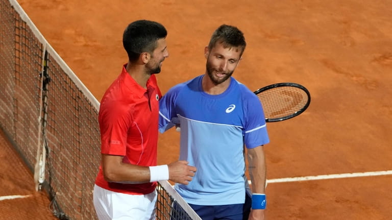 Serbia's Novak Djokovic, left, talks with France's Corentin Moutet at...