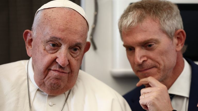 Pope Francis listens to Vatican spokesman Matteo Bruni aboard the...