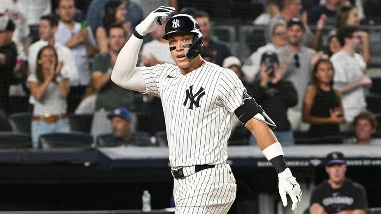 The Yankees’ Aaron Judge gestures as he scores on his...