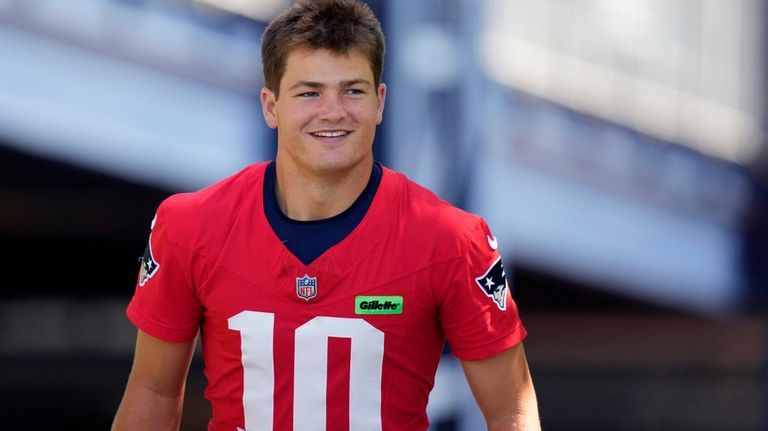 New England Patriots quarterback Drake Maye smiles while heading towards...