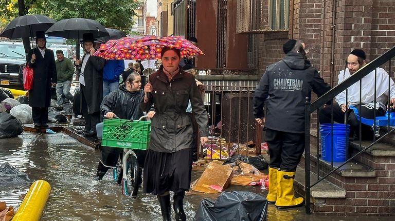 Pedestrians walk along a flooded sidewalk, Friday, Sept. 29, 2023,...