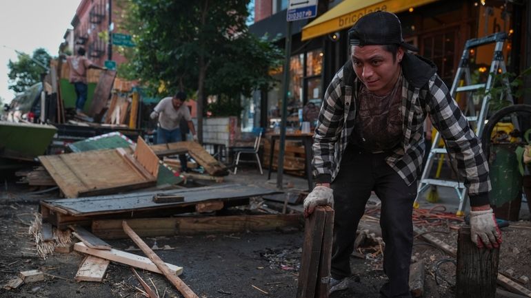 Workers demolish an outdoor dining shed outside Bricolage restaurant, Wednesday,...