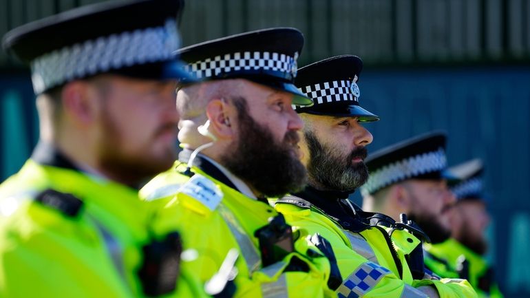 A line of policemen, coincidentally all sporting beards, stand guard...