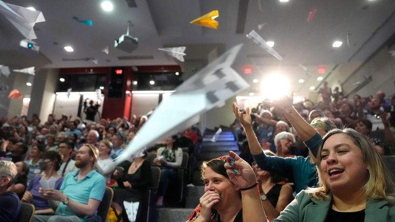 People in the audience throw paper airplanes toward the stage...