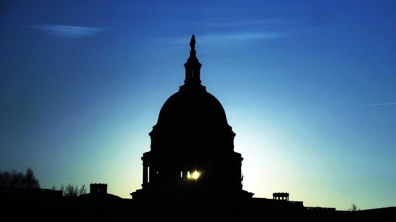 The Capitol Dome silhouetted against the rising sun in Washington,...