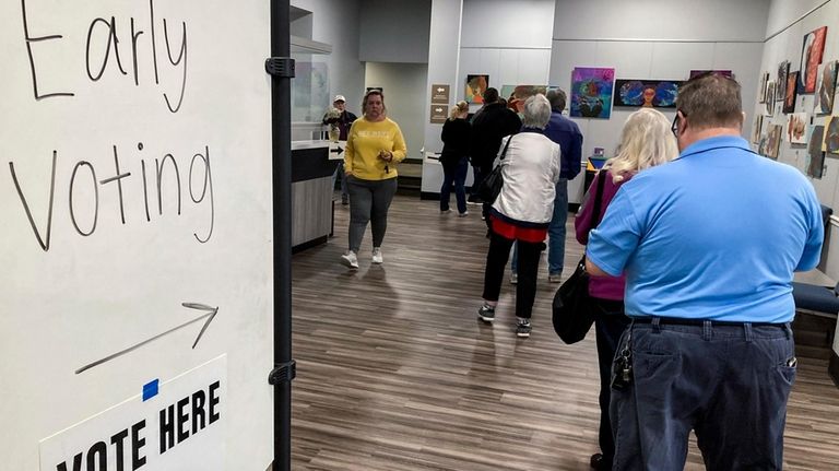 People wait in line to early vote Nov. 28, 2022,...