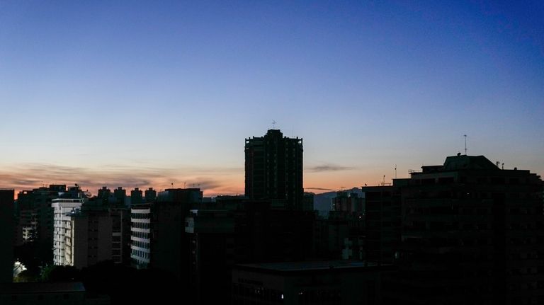 Buildings stand in darkness during a power outage in Caracas,...