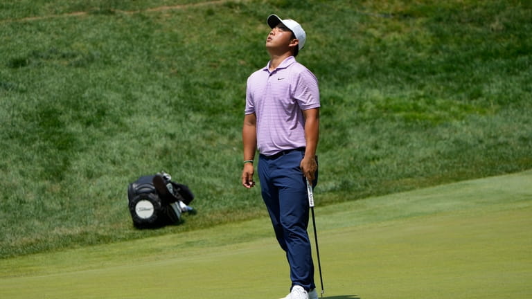 Tom Kim, of South Korea, reacts to a missed putt...