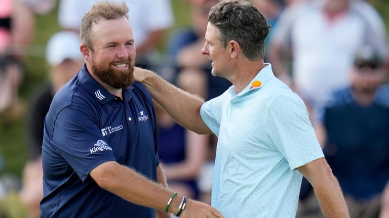 Justin Rose, of England, greets Shane Lowry, of Ireland, after...
