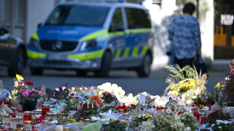 Flowers and candles are laid near the scene of a...