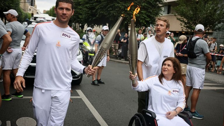 Press agency photographer Christina Assi, right, holds the Olympic torch...