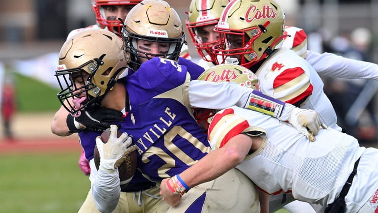 Kyle Messina of Sayville shakes off the tackle of Michael...