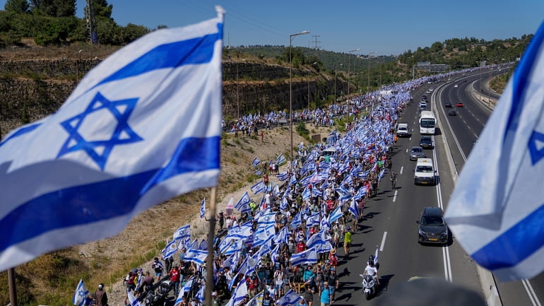 Thousands of Israelis march along a highway towards Jerusalem in...