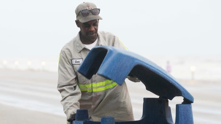 Galveston city worker Sean Kirby checks trash cans along Seawall...