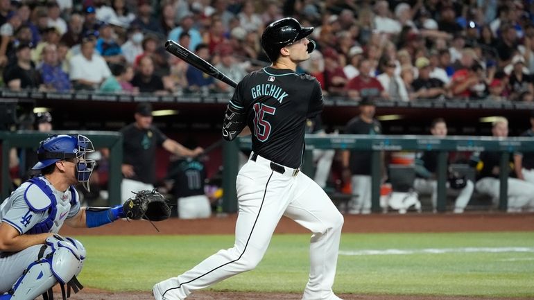 Arizona Diamondbacks' Randal Grichuk, right, watches the flight of his...