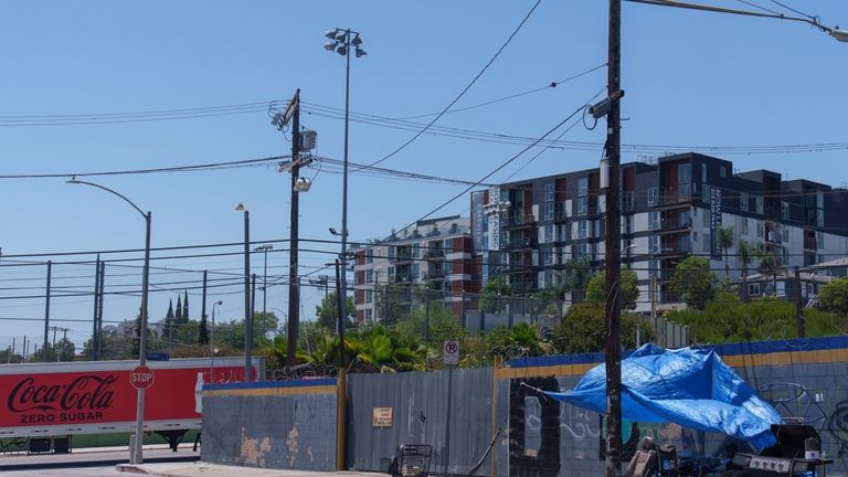 A homeless encampment sits across the street of a newly...