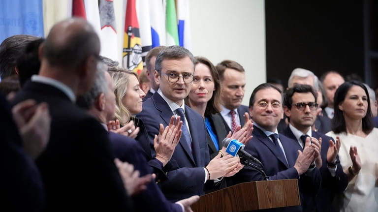Ukraine's Foreign Minister Dmytro Kuleba, center, is applauded by members...