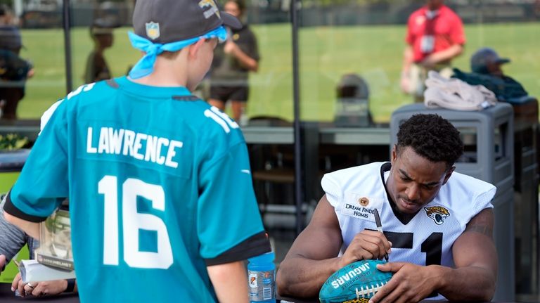 Jacksonville Jaguars linebacker Ventrell Miller, right, signs autographs for fans...