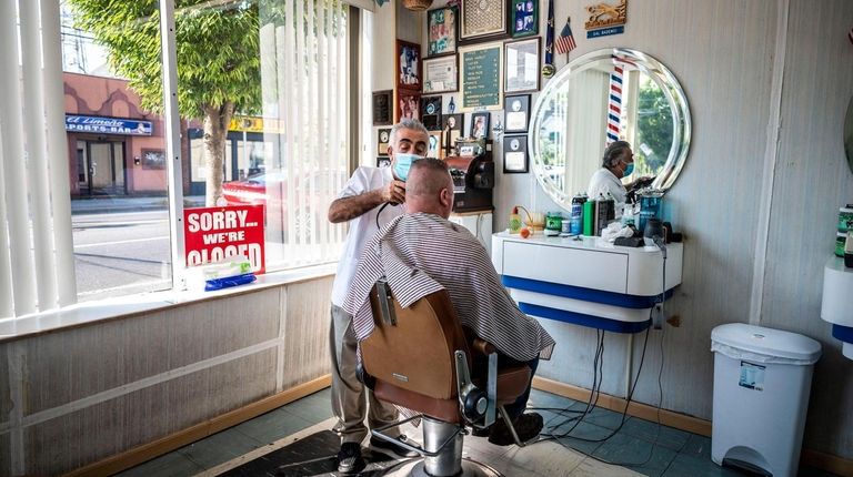 Sal Bademci works on a customer at his barbershop on...