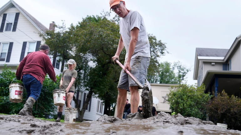 Homeowner Scott Mackie, right, shovels mud away from his home...